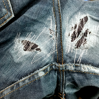 Stitches are sewn to hold denim patches in place as repair begins
